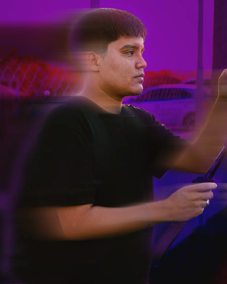 Davisson de perfil, iluminado de roxo, segurando um estabilizador